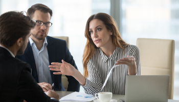 A woman and two men engaged in a business meeting