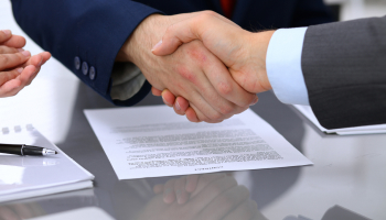 Two business professionals shaking hands over a document